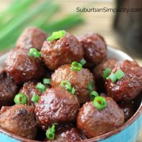 Crockpot meatballs in a bowl with fresh green onion slices on top.