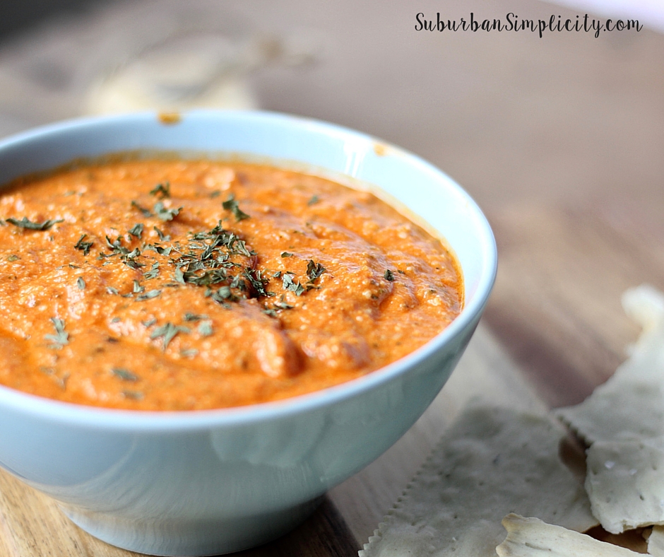Roasted Red Pepper and Artichoke Dip in a blue bowl with crackers next to it
