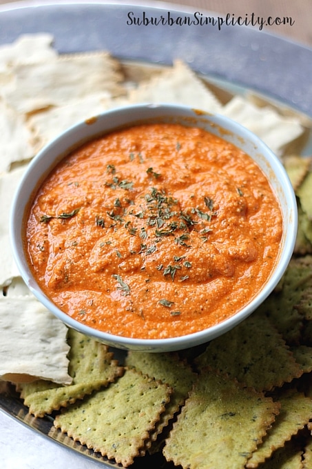 Roasted Red Pepper and Artichoke Dip with crackers on a serving plate