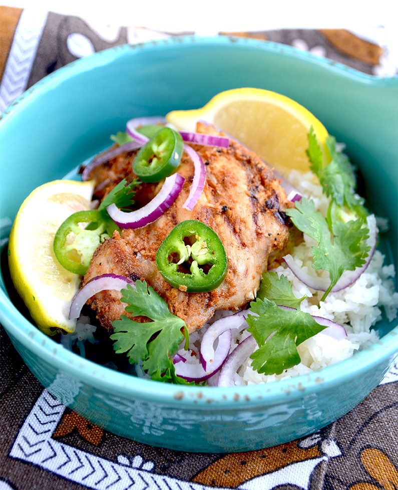 Tandoori Chicken on a rice in a bowl with lemon and onion