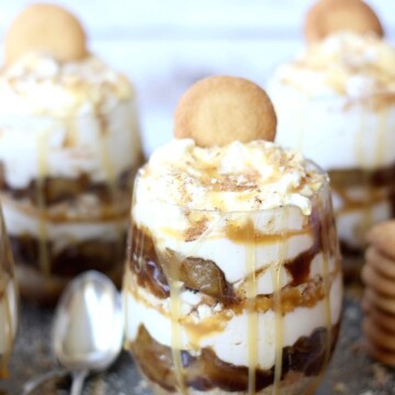 A caramel apple cheesecake with a cookie sticking out of the top and a spoon next to it.