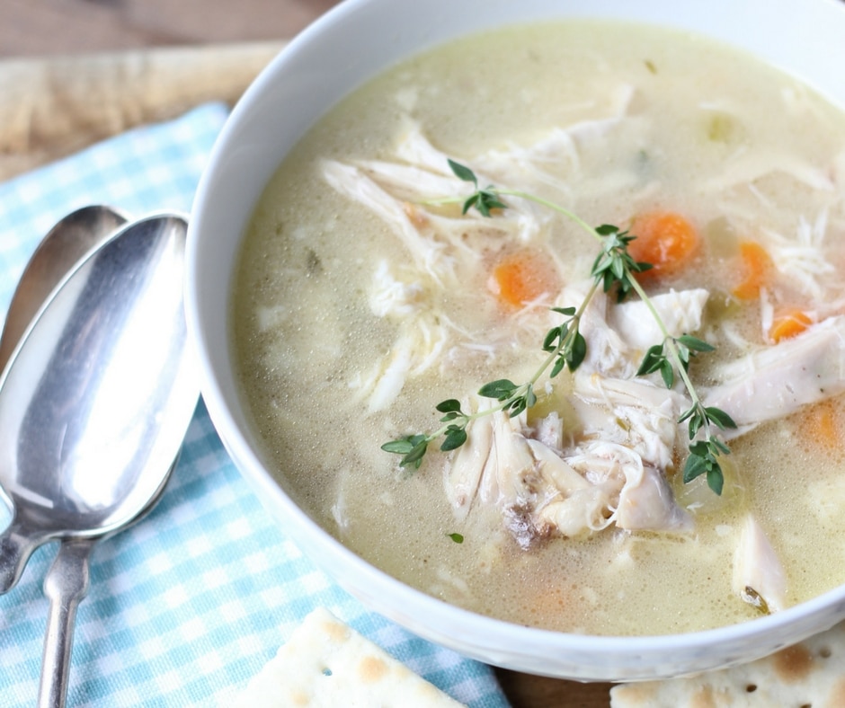 Homemade chicken soup in a bowl with thyme on top.