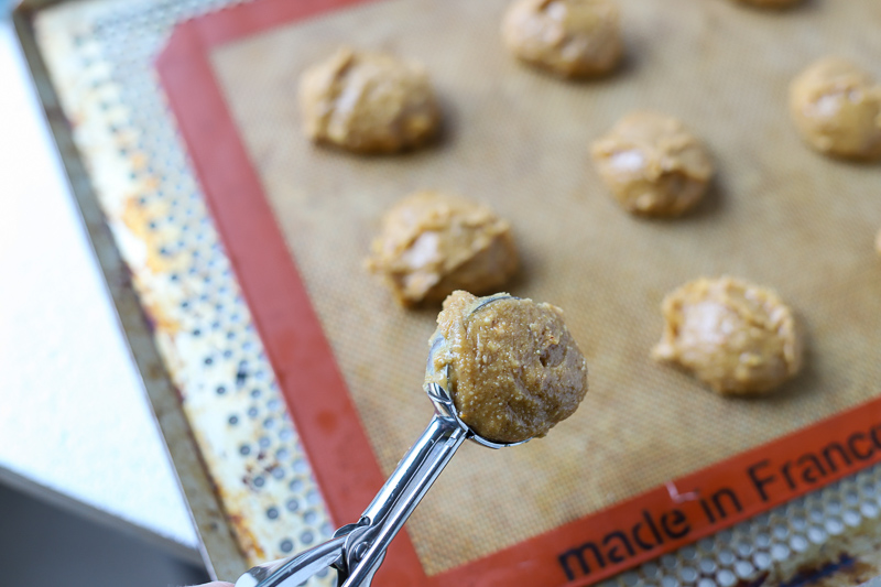 scooping gf peanut butter cookie batter onto cookie sheet