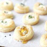 Goat cheese and honey bites with honey being dripped on them.