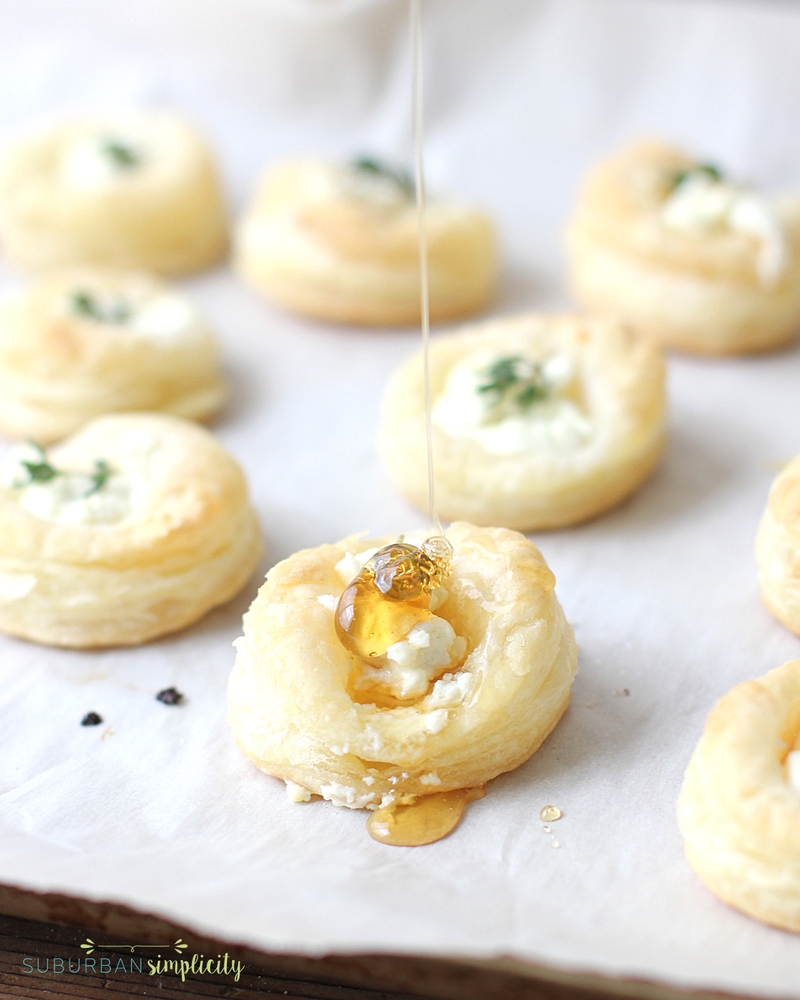 Goat cheese and honey bites with honey being dripped on them.