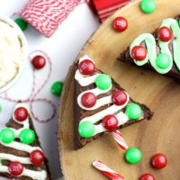 Brownies cut in the shape of Christmas trees with ribbons of frosting and M&M ornaments.