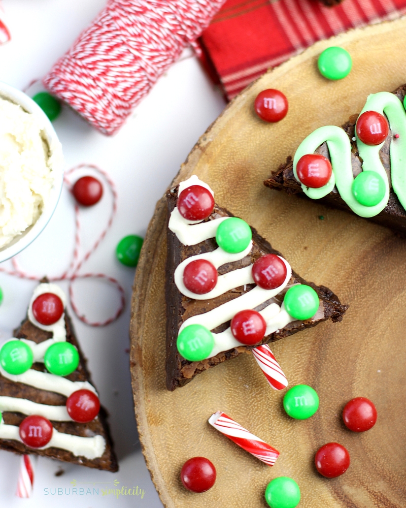 Brownies cut in the shape of Christmas trees with ribbons of frosting and M&M ornaments.