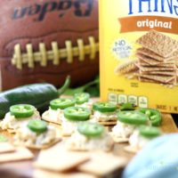 Wheat Thins with a cheesy dip topped with a jalapeño pepper.
