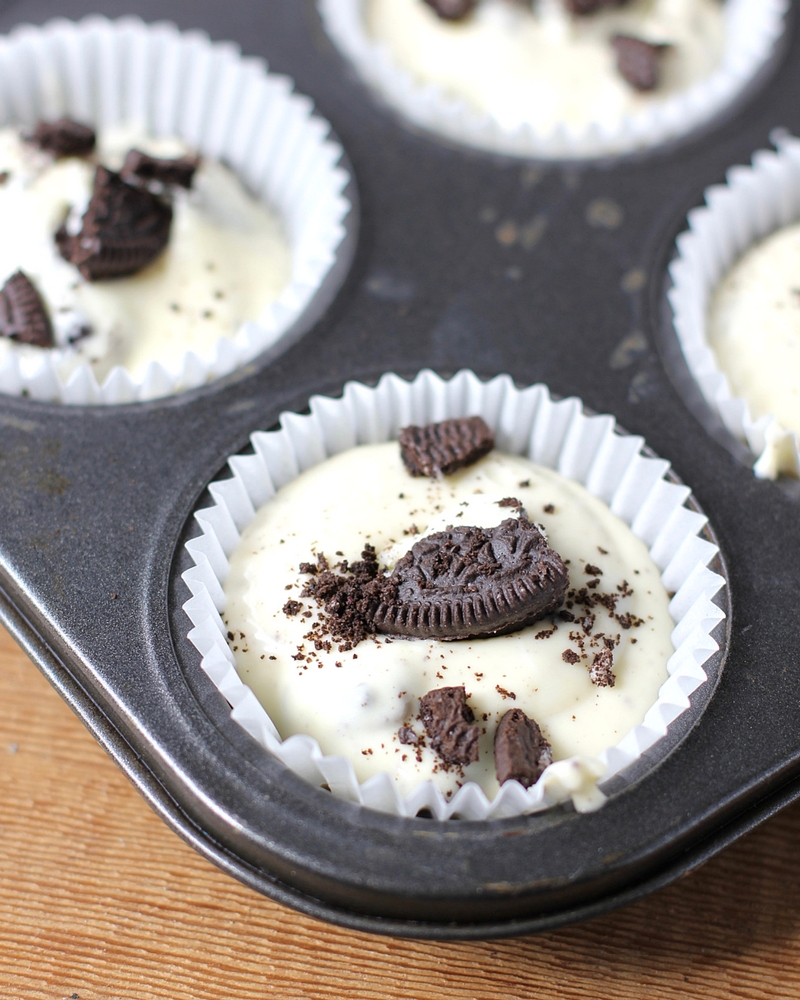 Muffin tins filled with Mini Cheesecakes with Oreo crust and topped with bits of Oreo Cookie.