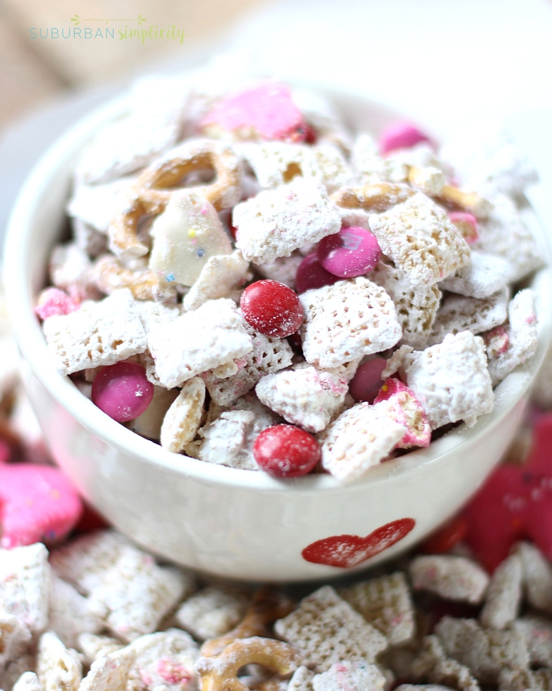Valentine's Day puppy chow made from chex cereal in a bowl with a heart on it.