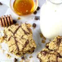 Chocolate Oatmeal Bars on a counter with a glass of milk and a dish of honey.