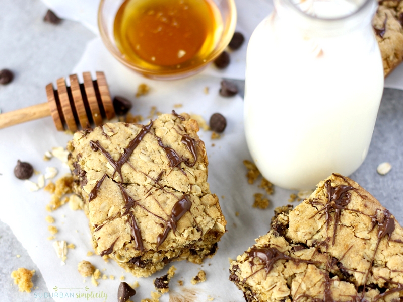 Oatmeal Chocolate Bars on a counter with a glass of milk and a dish of honey.