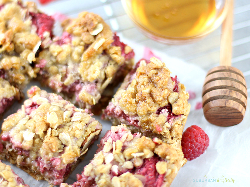 Raspberry Oatmeal Bars cut in squares with honey in the background