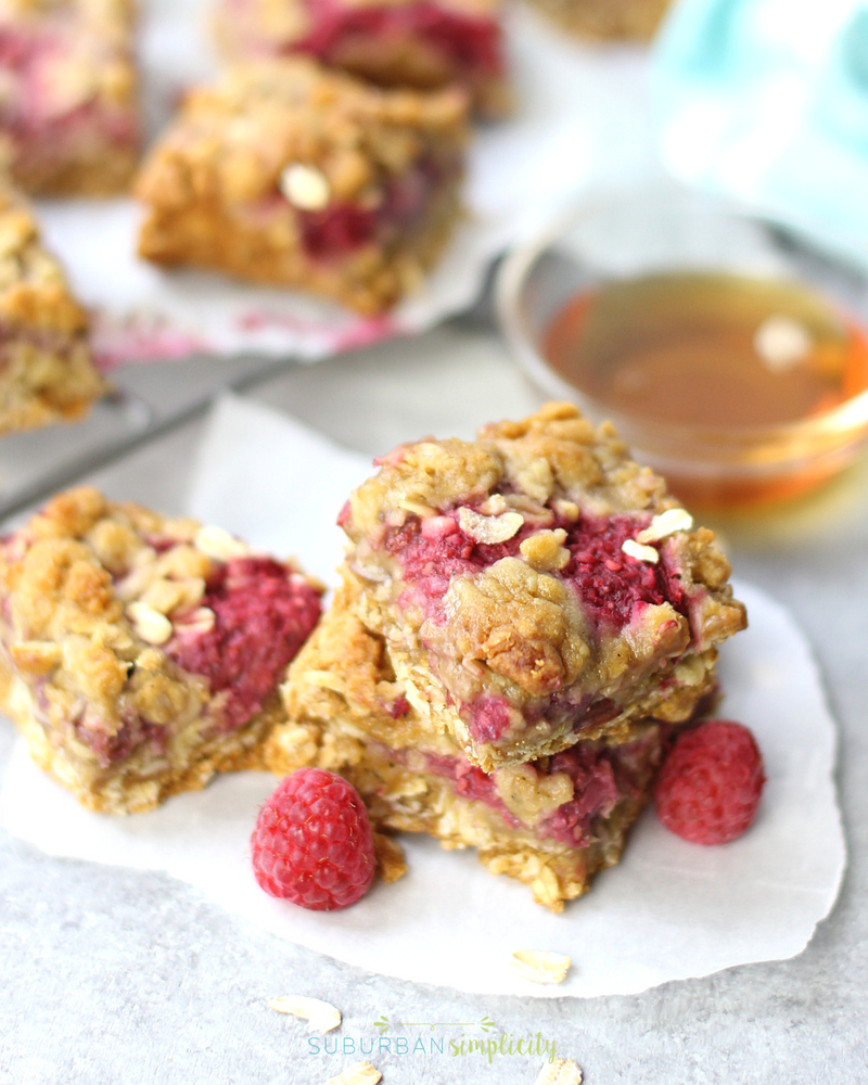 Raspberry oatmeal bars stacked together with fresh raspberry scattered about
