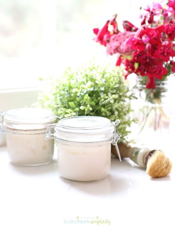 Jar of sugar scrub on the counter with flowers in the background.