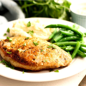 Parmesan Pork Chops on a plate with mashed potatoes and green beans.