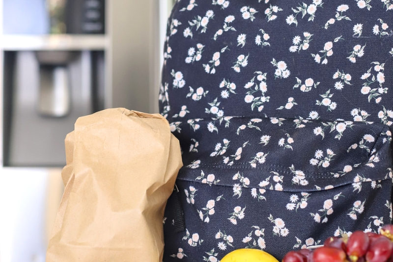Backpack on kitchen counter with fruit.