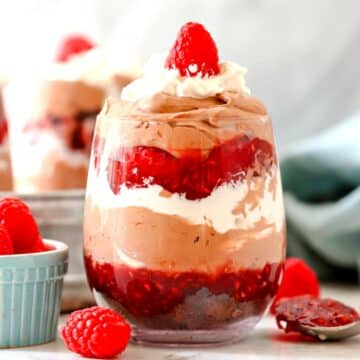 Raspberry trifle in a cup with raspberries next to it.