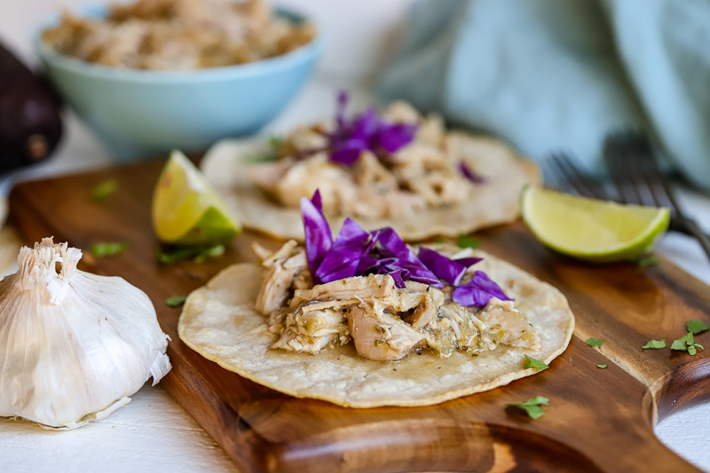 Chicken Salsa verde on a tortilla on a cutting board.