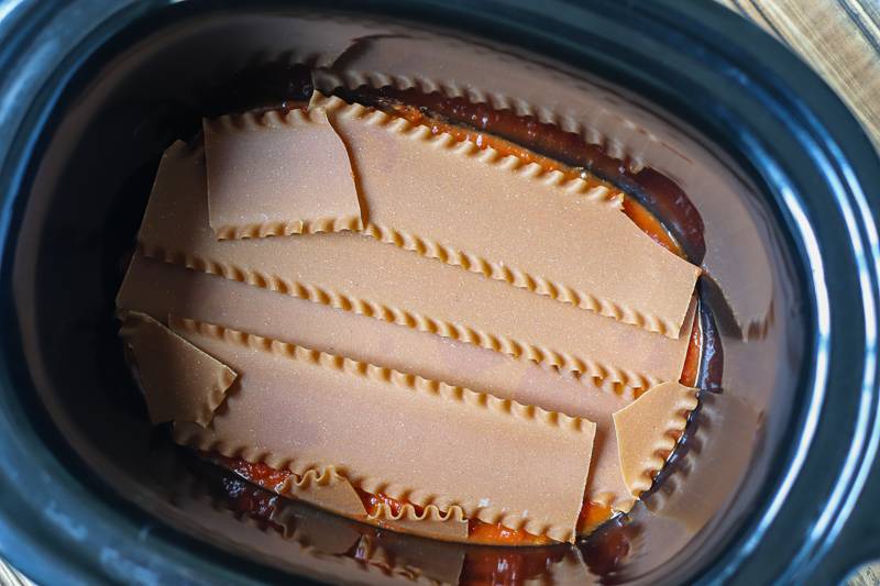 lasagna noodles being layered in crockpot