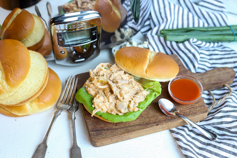 Buffalo chicken sandwich sitting on top of a wooden cutting board.