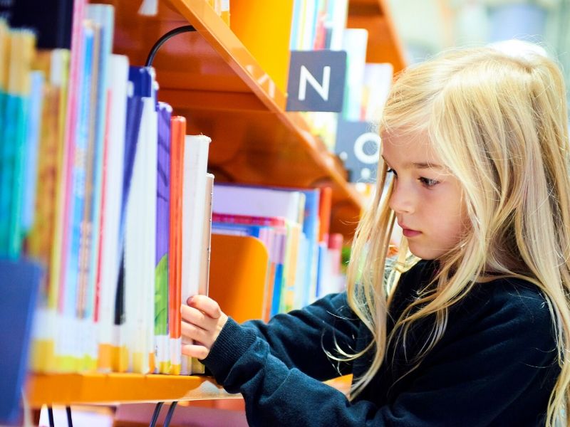 child picking books at the library