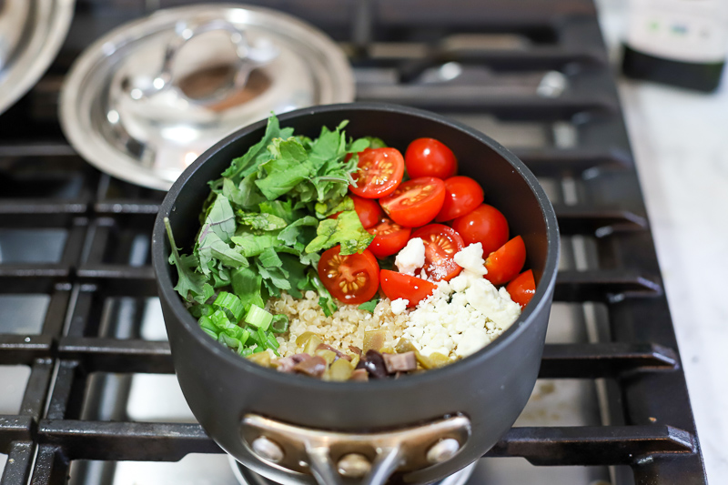 Quinoa, tomatoes, feta cheese, and olives in a pot