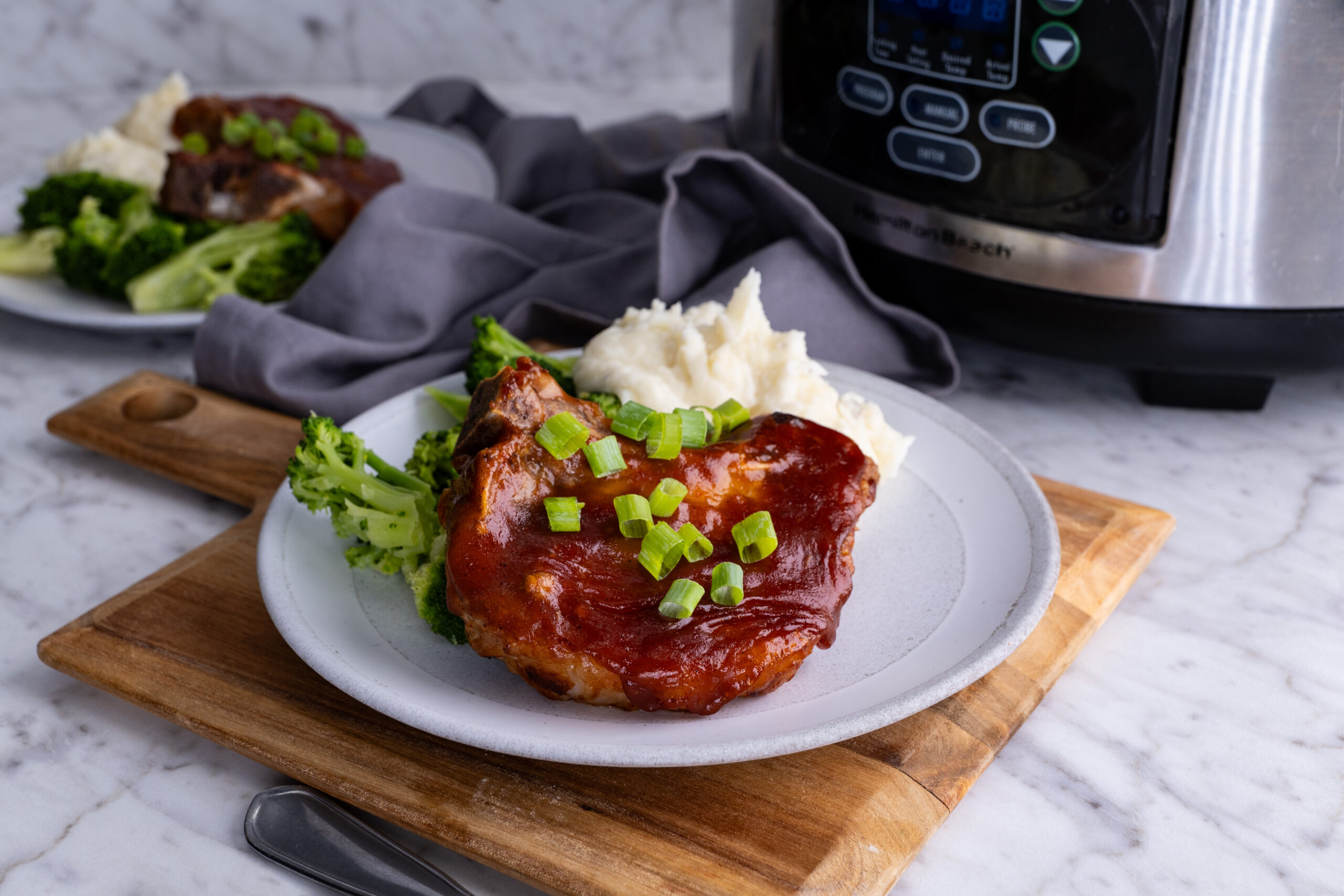 Slow cooker Pork chop on a plate with broccoli.