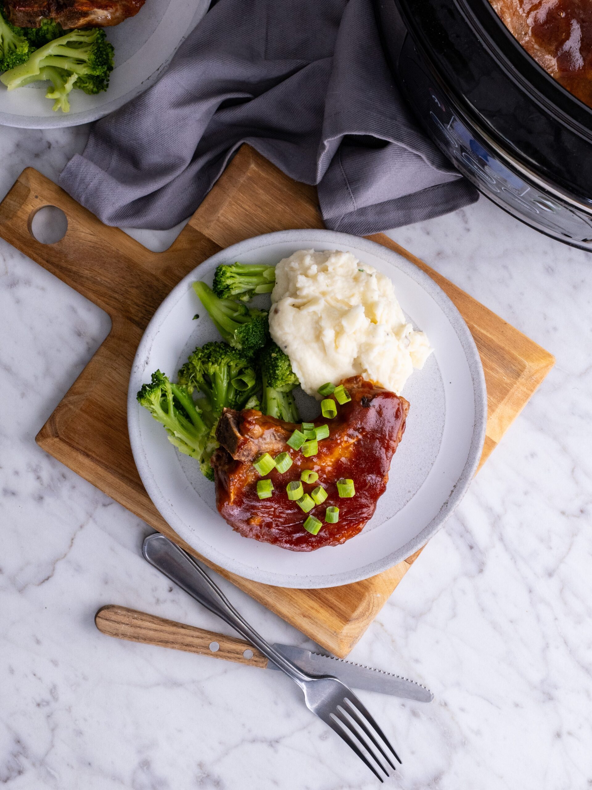 Slow cooker Pork chop on a plate with broccoli.