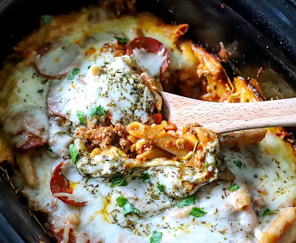 slow cooker pizza casserole with a serving spoon in it.