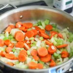 carrots, onions, and celery being cooked in a pan