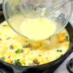 eggs being added to a sausage frittata