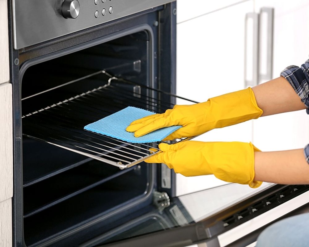 someone cleaning an oven with rubber gloves
