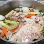 carrots, celery, onions and a turkey carcass in a pot