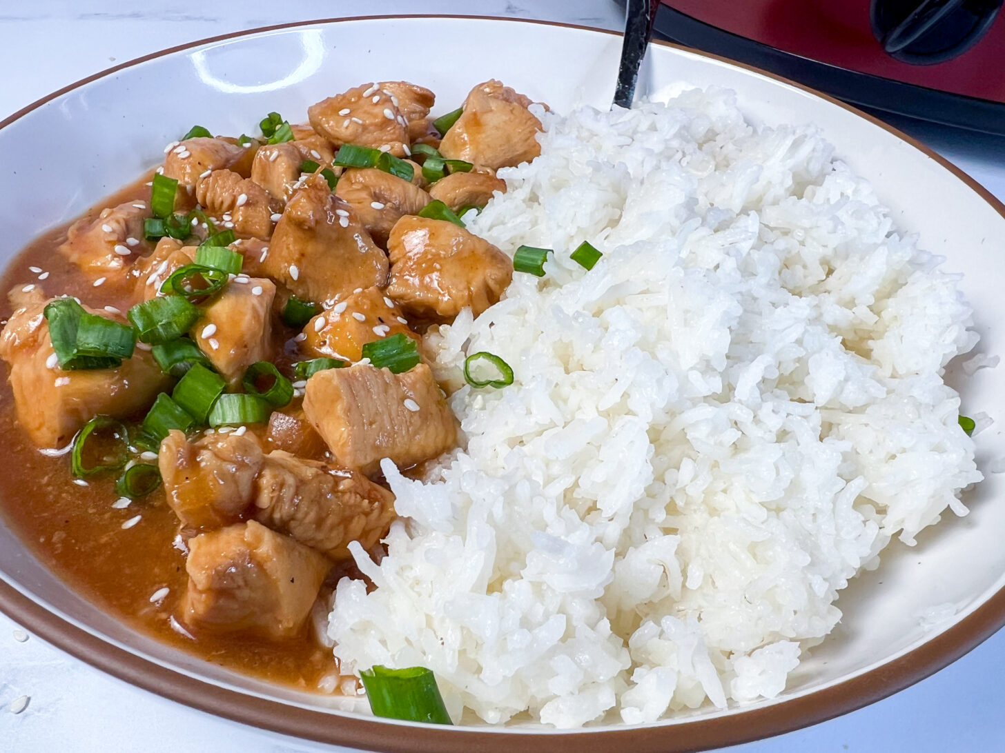 Crock Pot sesame chicken plated in a bowl with white rice