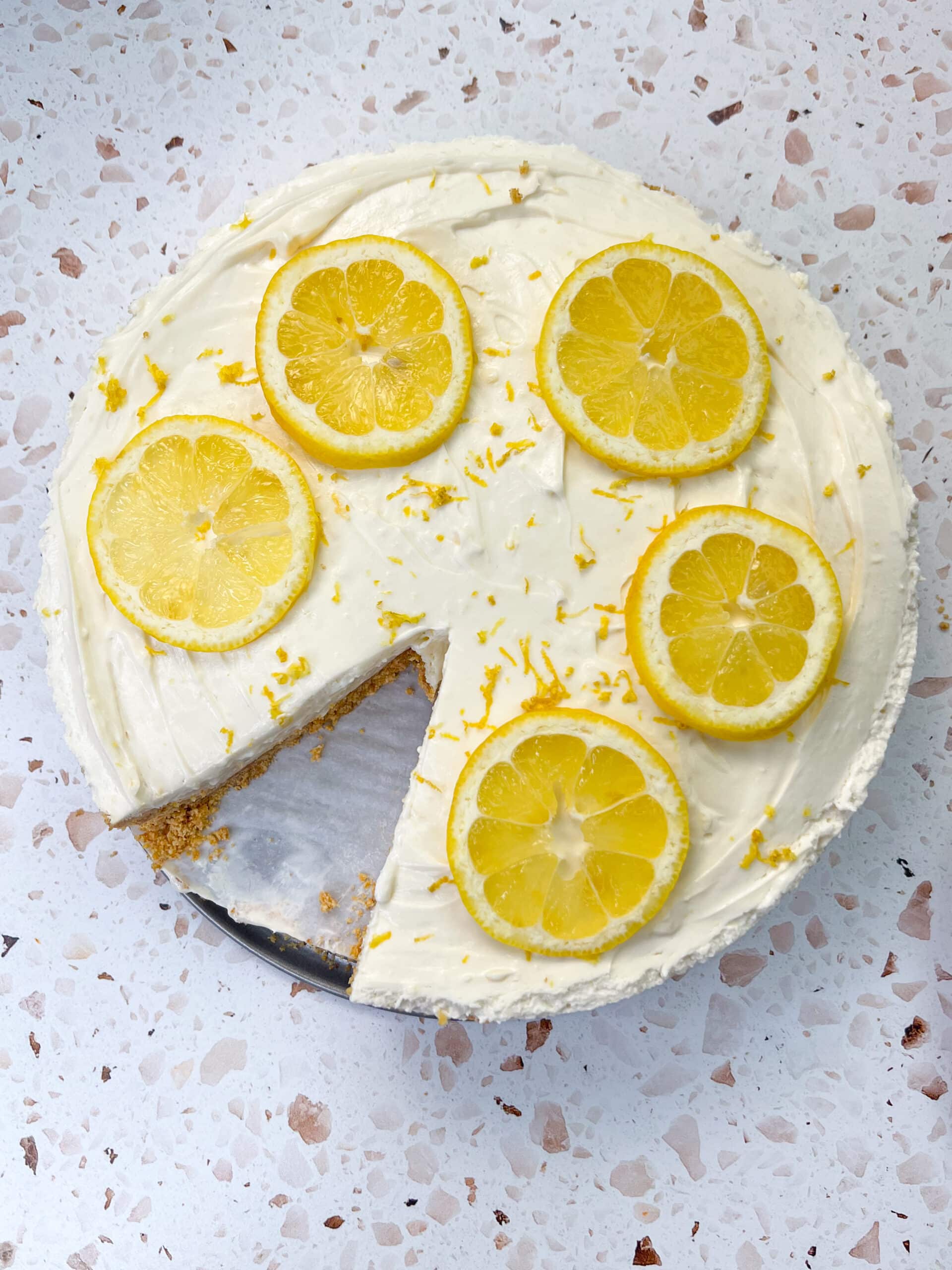No bake lemon cheesecake topped with lemon slices with a piece cut out