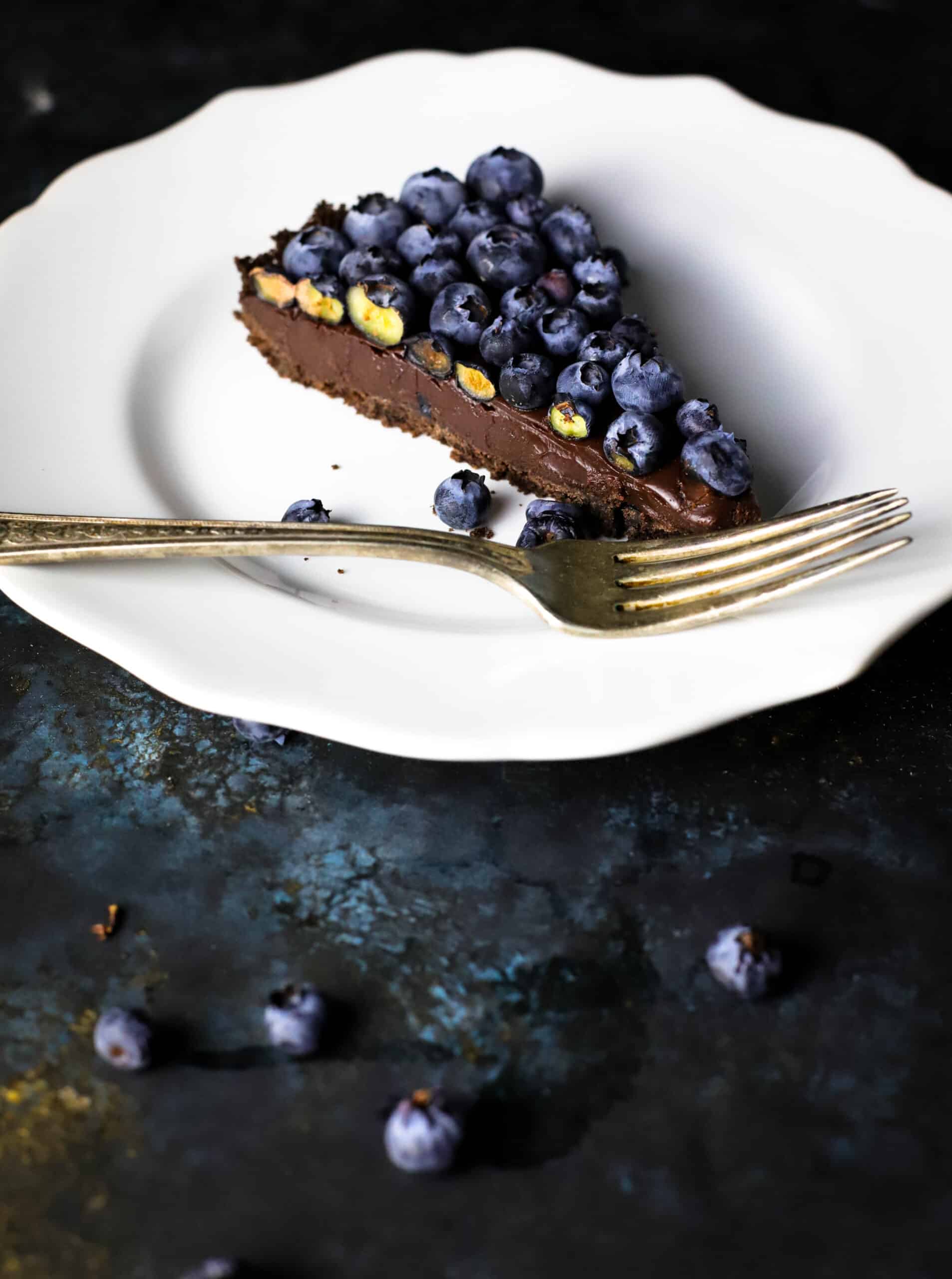 Whole slice of Chocolate ganache tart slice with blueberries