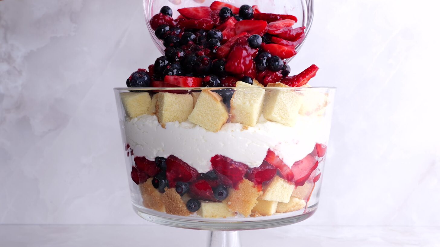 Jam coated berries being poured into berry trifle dish