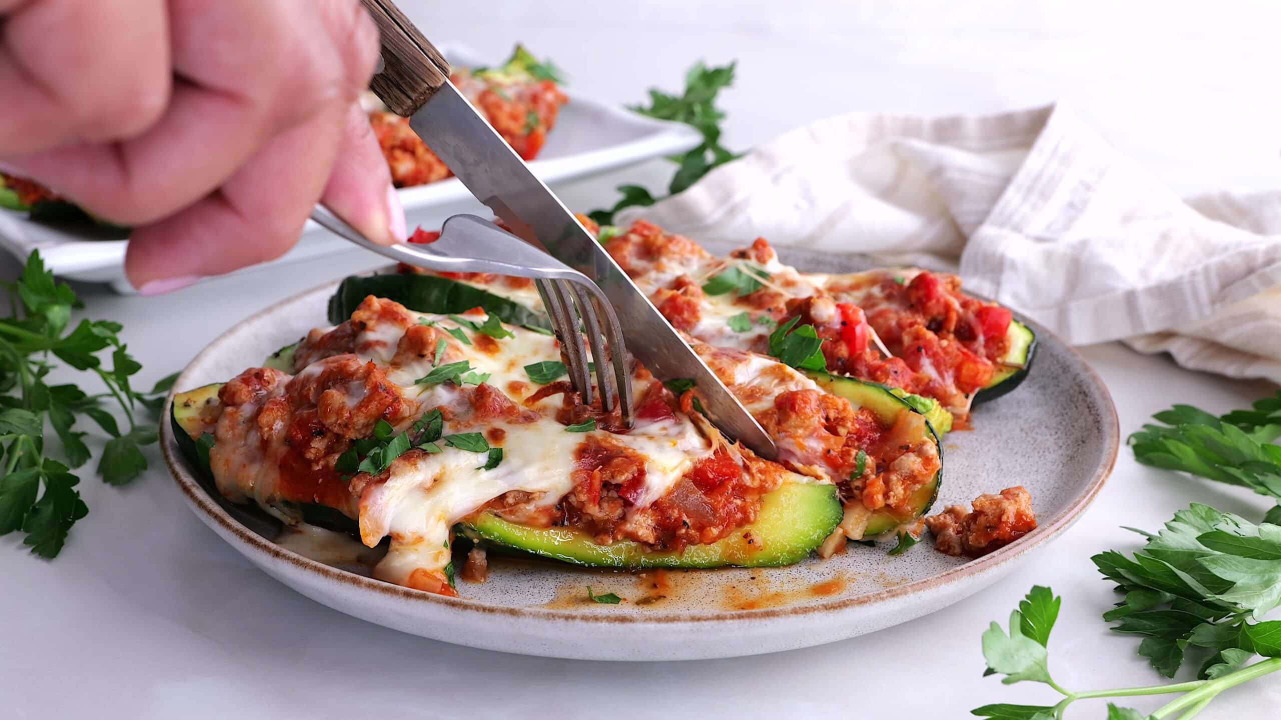 Person cutting into stuffed zucchini boats