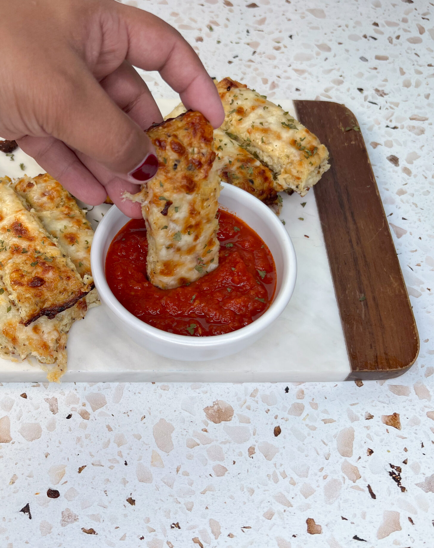 Dipping cauliflower breadsticks in marinara sauce