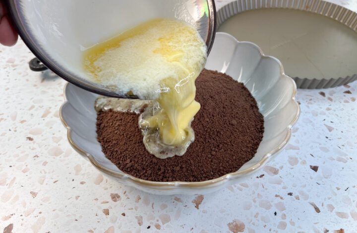 process shot, butter being poured into chocolate graham cracker crumbs