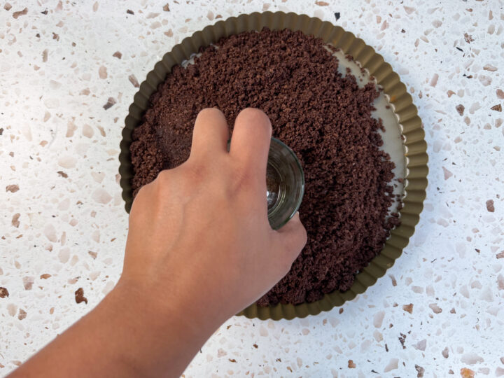 Crust being pressed into tart pan for chocolate ganache tart