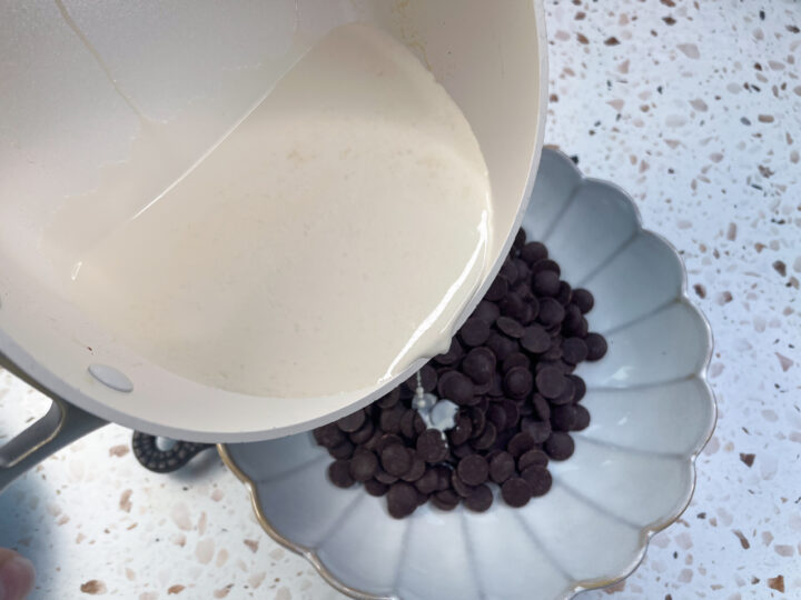 Pouring cream over dark chocolate chips for chocolate ganache tart