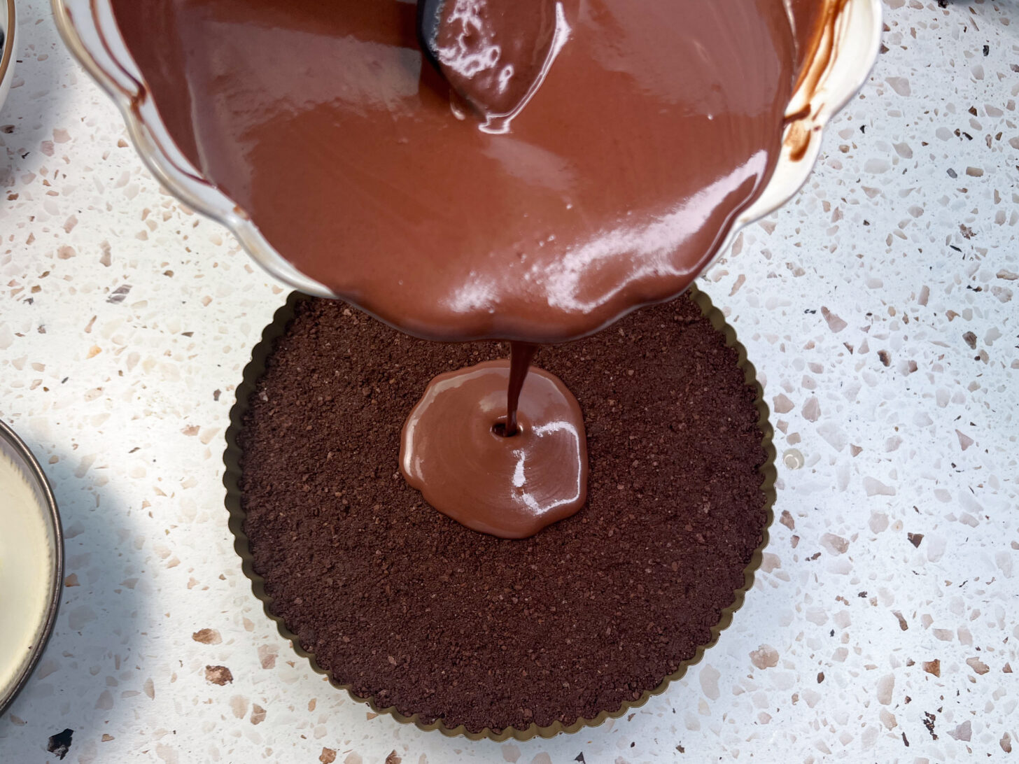 dark chocolate ganache being poured onto crust