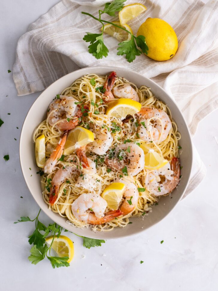 Shrimp Scampi Pasta in a bowl, garnished with fresh herbs and lemon slices
