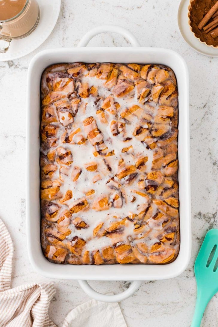 Golden baked cinnamon roll casserole drizzled with icing in a 9 x 13-inch baking dish