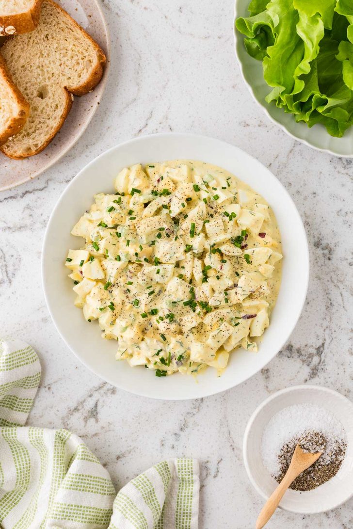 Creamy egg salad with celery, red onion, and fresh dill in a white bowl
